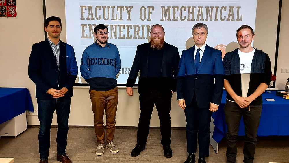Eine Gruppe Männer steht vor einer Bildfläche mit der Aufschrift Faculty of Mechanical Engineering