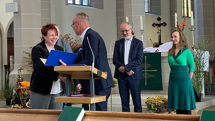 In a church at the altar, Cornelia Müller is delighted to receive the scholarship from the Chairman of the Foundation Board, Dr. Uwe Koch.