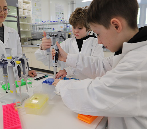 Two students at the pipetting station in the laboratory working with pipettes.