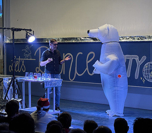 Ein Teammitglied im aufblasbaren Eisbärkostüm im Gespräch mit dem Tanzlehrer.