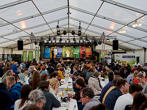 Hundreds of guests sit on beer tent sets in the marquee.