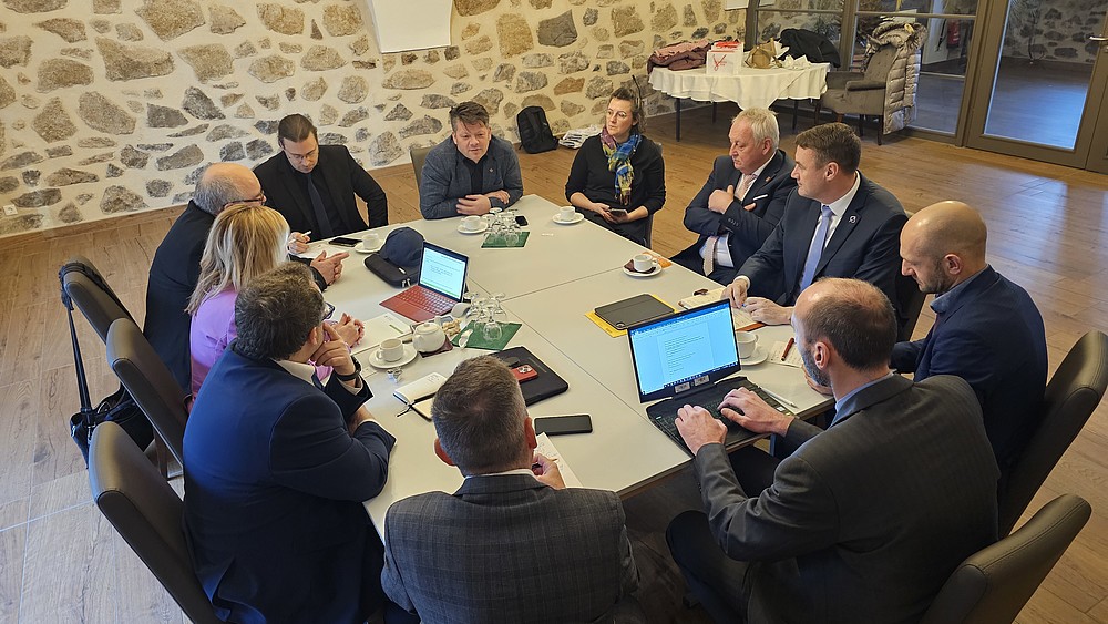 Many representatives of cities and educational institutions sit around a table and talk.