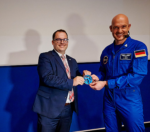 Alexander Gerst presents the Rector with the Blue Dot mission patch in the Audimax.