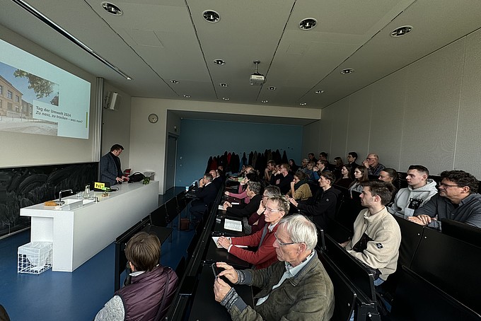 Guests sit on the rows of seats in the lecture hall and listen to a lecture.