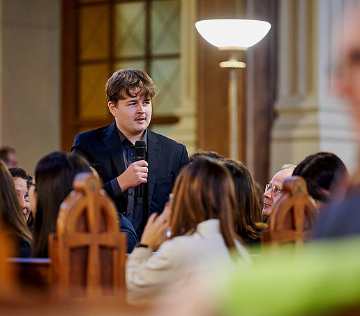 Student stands and speaks into the microphone.