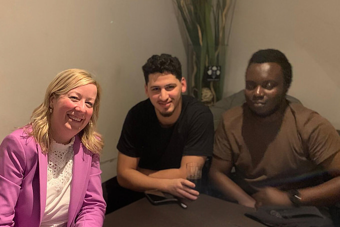 Prof. Dr. Sophia Keil is sitting at a table in the Dezi Bar talking to two colleagues. The atmosphere is relaxed and the three people are smiling during the conversation.