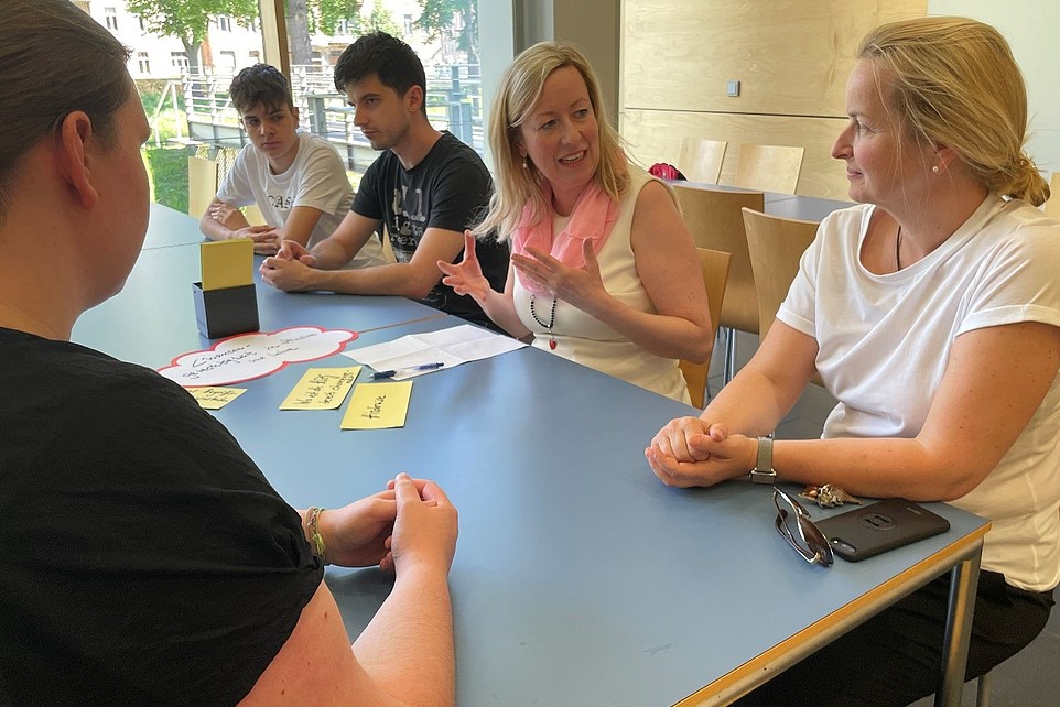 Pupils, staff and the Vice Principal are sitting at a table with conversation cards in front of them.