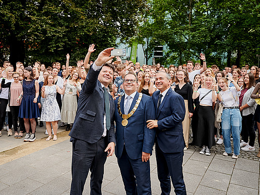 Eine große Gruppe Neuimmatrikulierte und der Rektor stehen auf dem Görlitzer Campus und lachen in die Drohnenkamera.