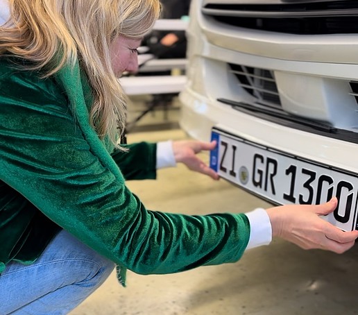 The pro-rector attaches the license plate to the Sprinter.