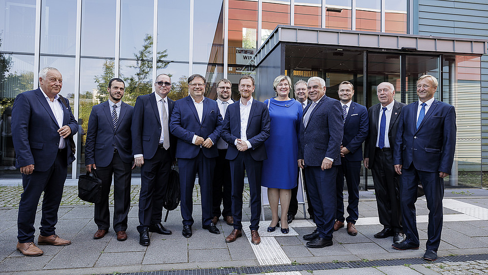 The German-Czech delegation stands in front of the entrance to the Blue Box on the Görlitz campus for a group photo.