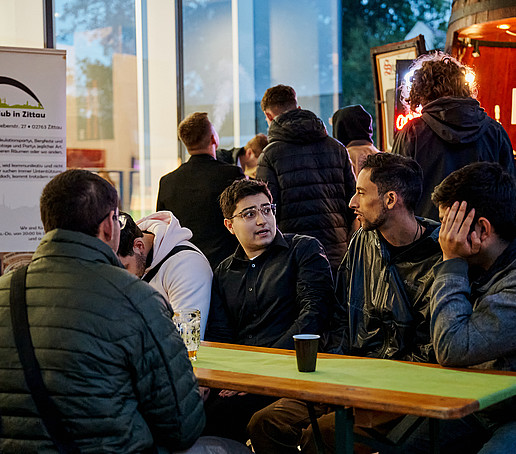 Studierende sitzen draußen und unterhalten sich.