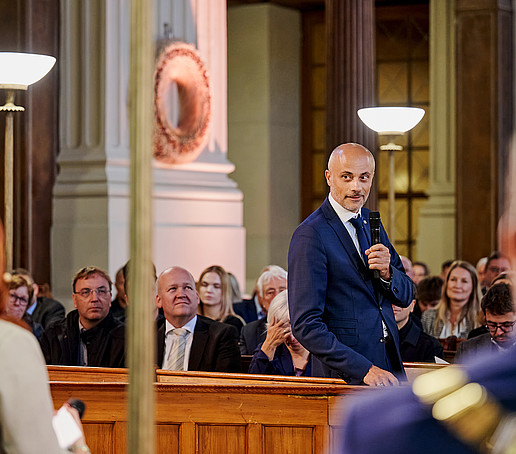 Prof. Maiwald stands and speaks into the microphone.