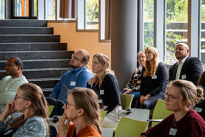 Group of people listen attentively to a lecture in a bright seminar room.