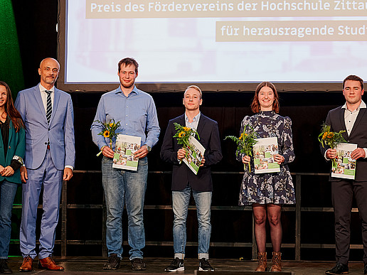 Association members and award winners with their certificates on stage.