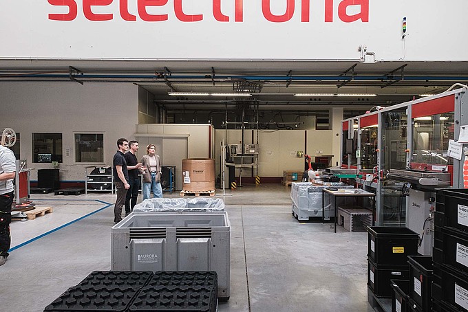 Großes Logo von Selectrona an der Wand in einer Fabrikhalle.