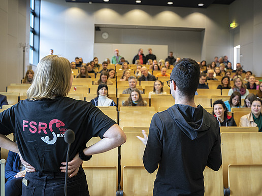 Two students, moderator Lennard and Sahra from the Social Sciences student council, stand in front of seated prospective students in the lecture hall and provide information about the courses on offer and campus life at Zittau/Görlitz University of Applied Sciences. The picture shows the open and communicative way in which the university welcomes prospective students and supports them in their decision-making process. It conveys a lively atmosphere and shows how committed and enthusiastic students and staff at the university are about inspiring prospective students to study at Zittau/Görlitz University of Applied Sciences.