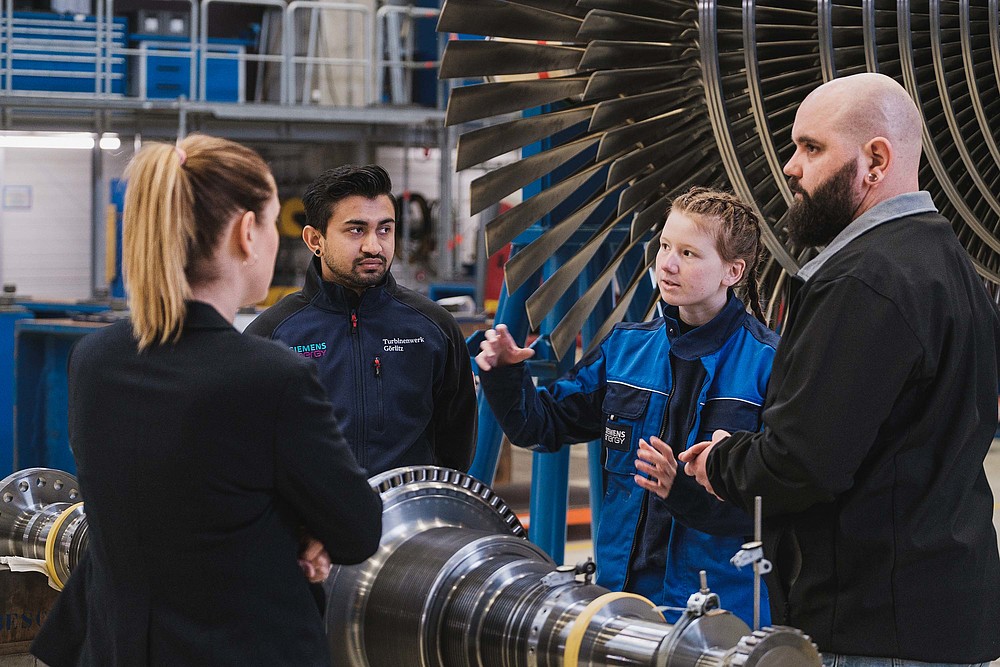 Four people in front of an industrial turbine