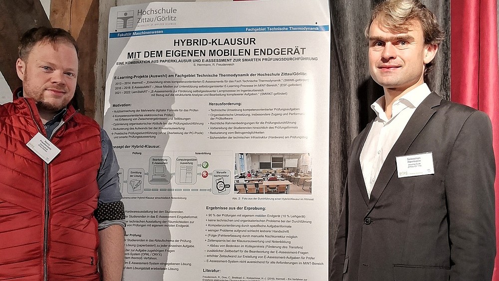 Dr.-Ing. Sebastian Herrmann and Ronny Freudenreich, M.A. stand in front of their presentation poster.