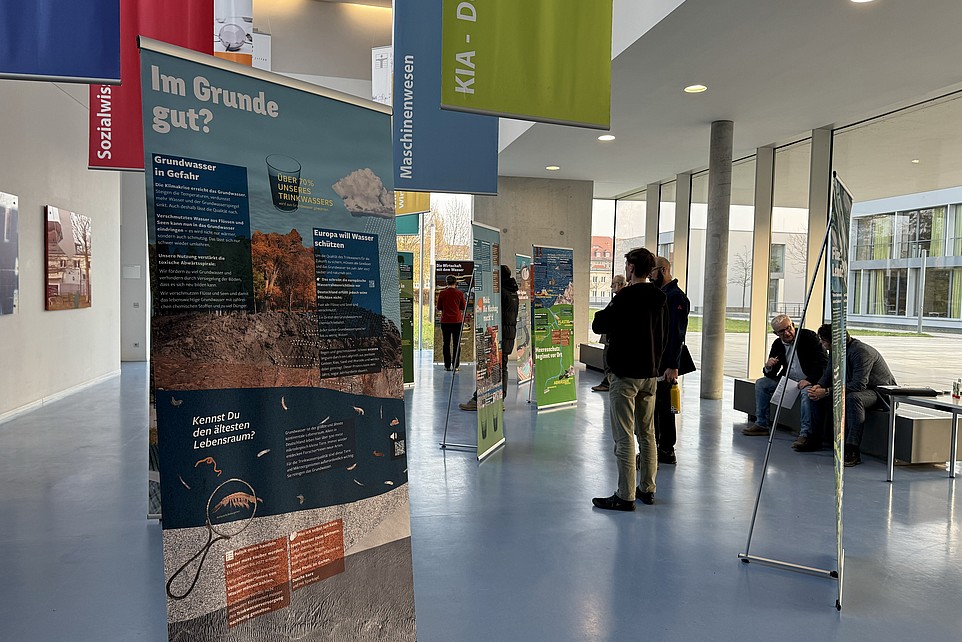 Guests stand in the foyer in front of exhibition roll-ups.