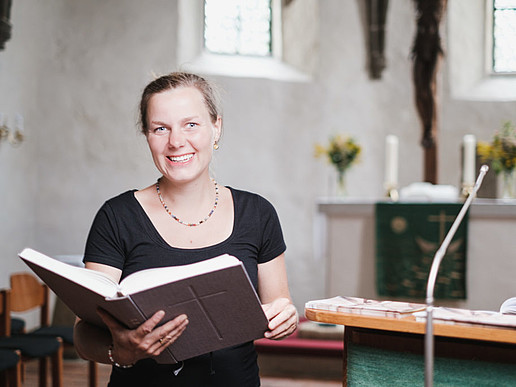 Frau Mahling sitzt in Kirchenbank, mit aufgeschlagener Bibel