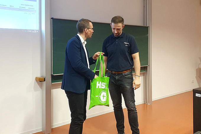 Prof. Kornhuber presents Mr. Schumann with a green HSZG bag.