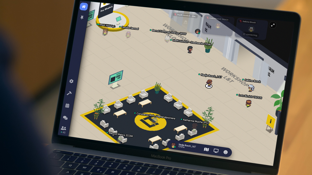 A Macbook shows a virtual world with a large corridor from which rooms lead off.