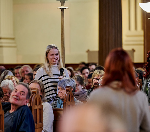 A student stands and speaks into the microphone.