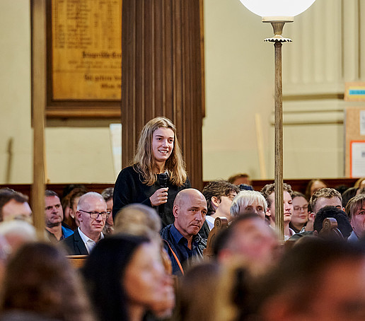 A student stands and speaks into the microphone.