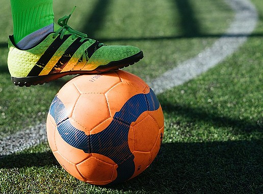 A football on the grass with a soccer boot on it