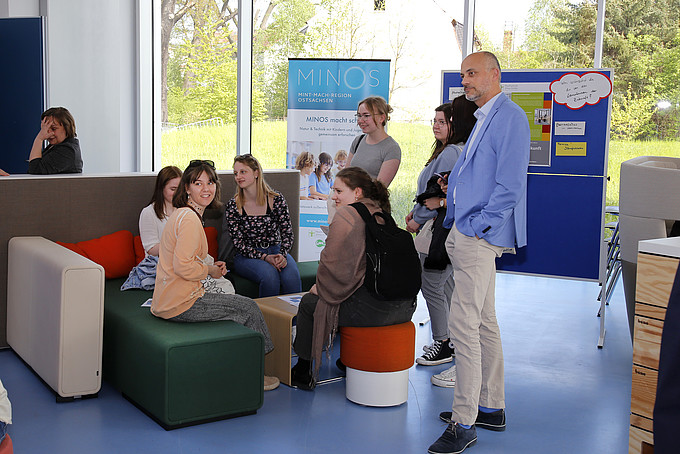 Guests at the Teaching Day chat in the foyer of House Four using modern seating from the furniture exhibition.