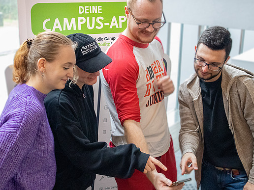 Students look at a cell phone together.