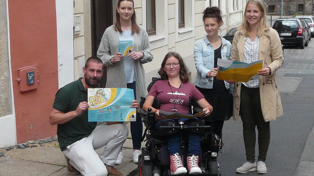 Young people holding a map of Görlitz's old town for people with reduced mobility.