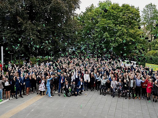 Graduates on campus throw their graduate hats in the air.