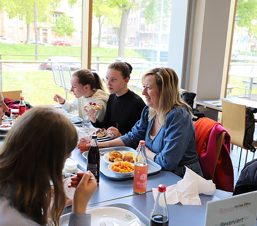 Die Prorektorin sitzt mit Schülerinnen am gedeckten Tisch in der Mensa.