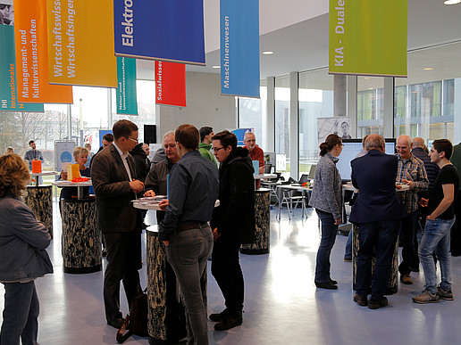 Prospective students and university members stand at advice tables in the foyer of the Peter-Dierich-Haus in Zittau.