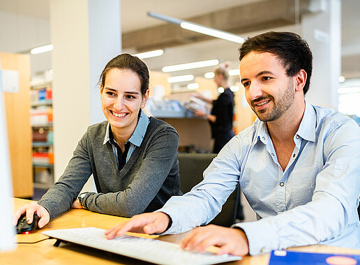 A woman and a man working together on a computer.