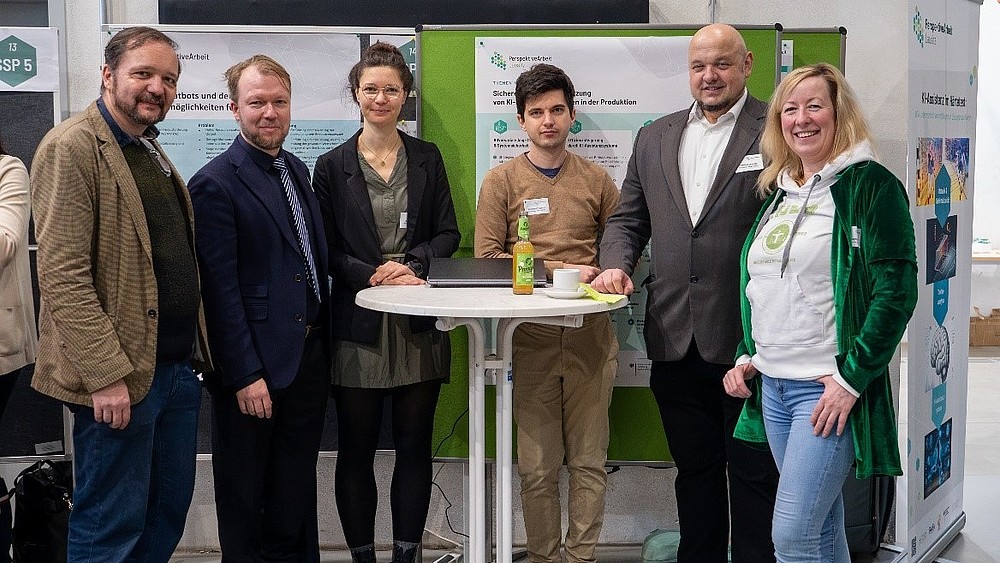 Das PAL-Team der Hochschule Zittau/Görlitz steht um einen weißen Stehtisch herum und lächelt in die Kamera.