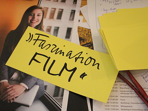 Ein Notizzettel mit der Aufschrift Faszination Film liegt auf Workshopmaterialien auf dem Tisch.