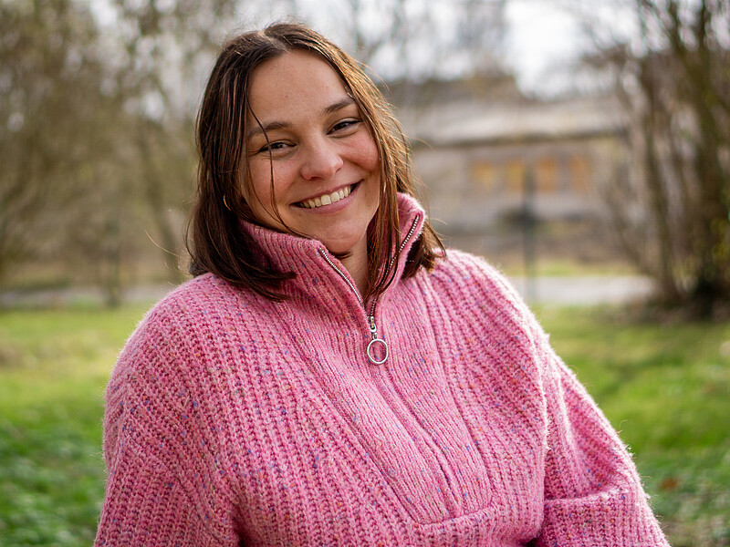 Alexandra Espinosa Rojas sits on a meadow.