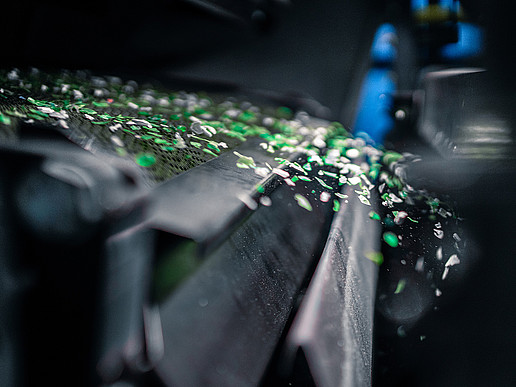 Green plastic particles fly out of a machine