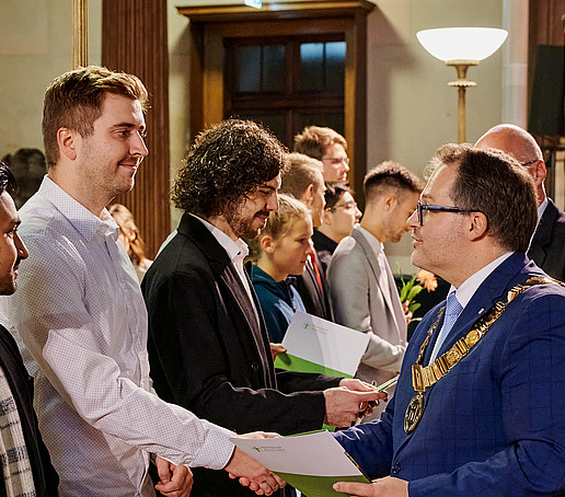 Der Rektor schüttelt die Hand eines Deutschlandstipendiaten bei der Urkundenübergabe.