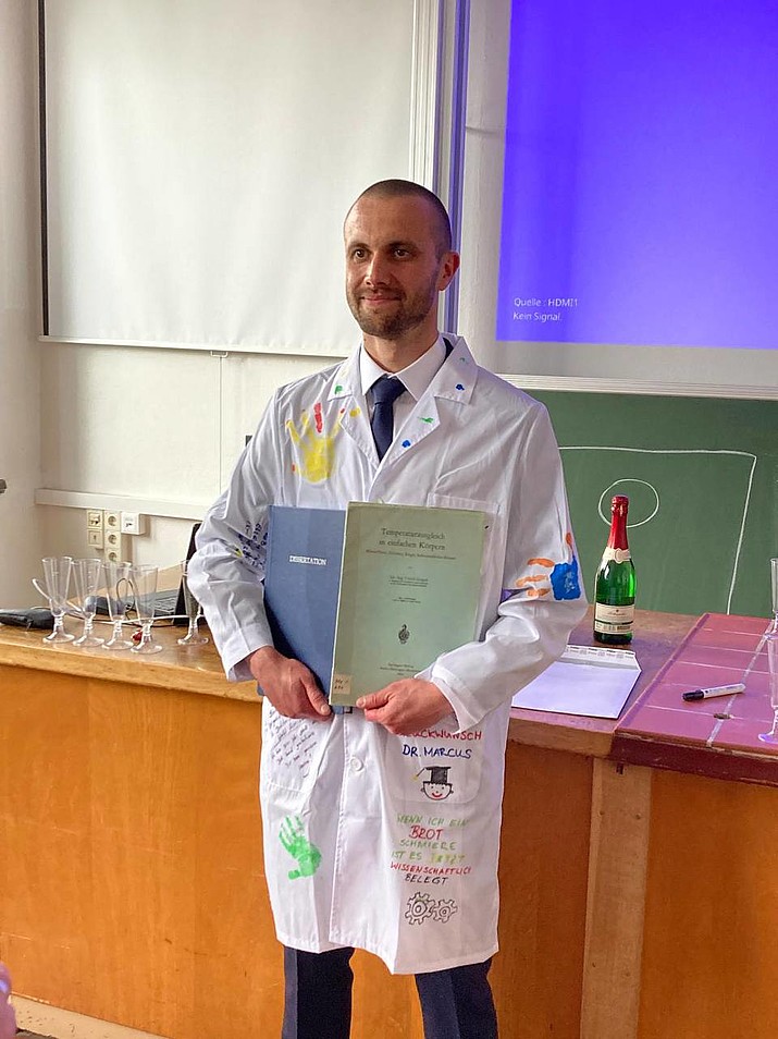 Marcus Rohne holds his certificate in the lecture hall.