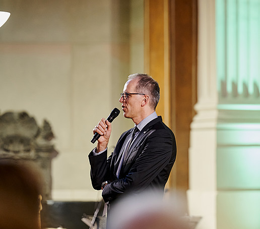 Mario Linack holds a microphone in his hand.