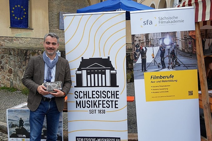 A representative of the Silesian Music Festival stands next to his roll-up.