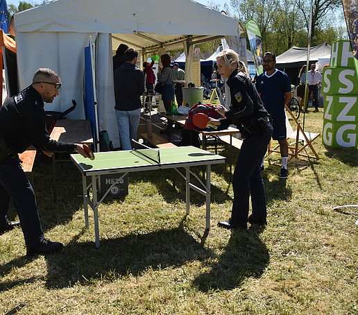 Two policemen play table tennis in front of the tent.