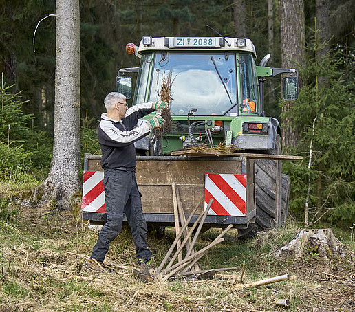 A forestry worker in front of a tractor in the forest.