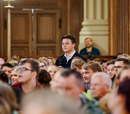 Student stands and speaks into the microphone.