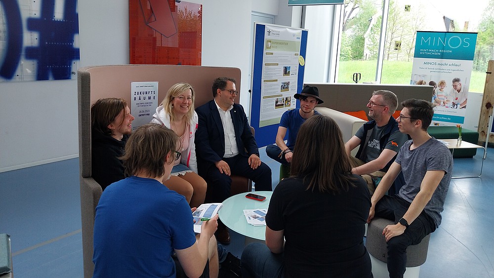 Rector and Vice-Rector sit with students in the furniture exhibition.