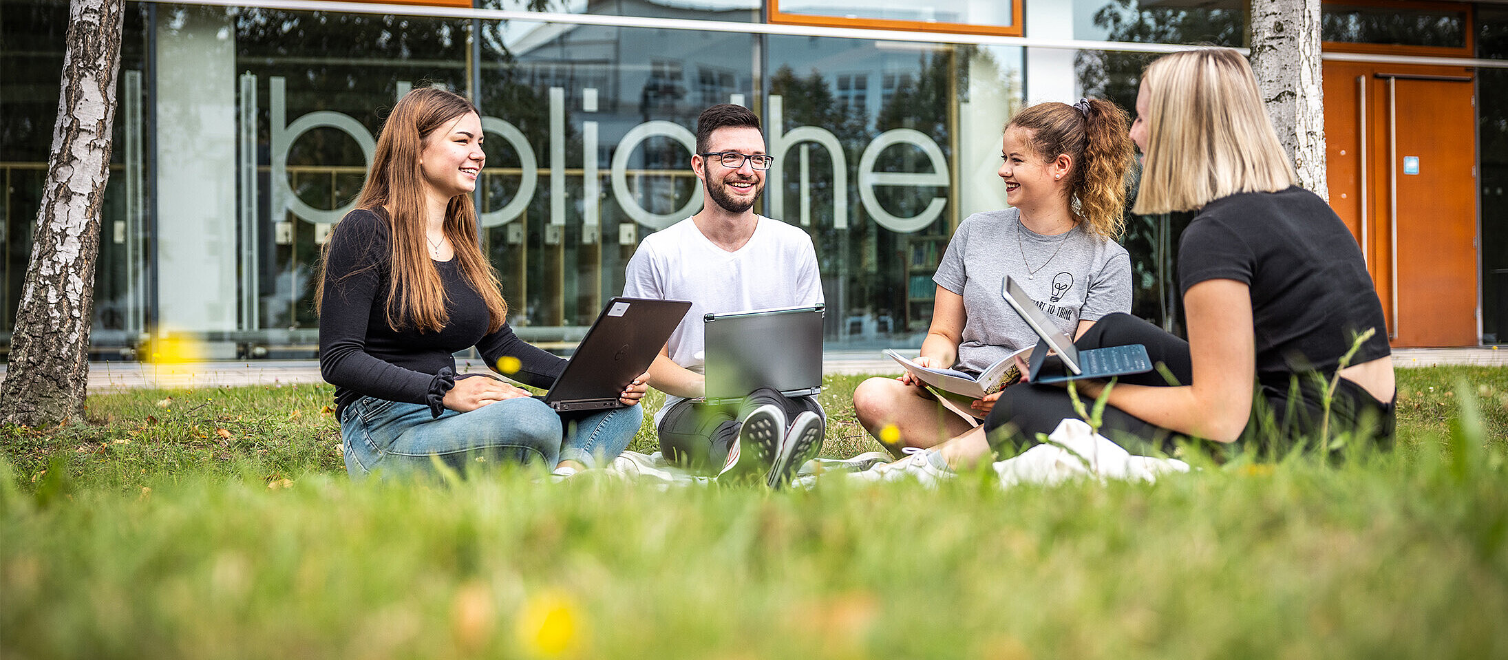 Students sit on the lawn in front of the canteen in Zittau.