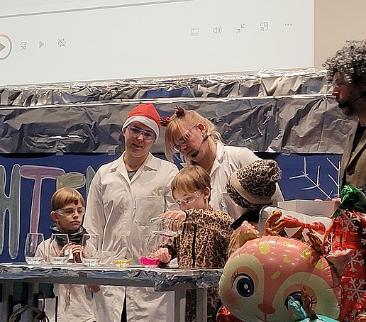 Children and lab assistants experiment on stage.